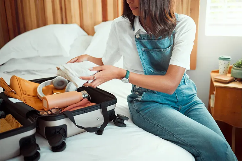 Woman packing suitcase on bed